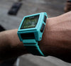 A blue Nixon Base Tide Pro sustainable digital watch shows 12 o'clock.