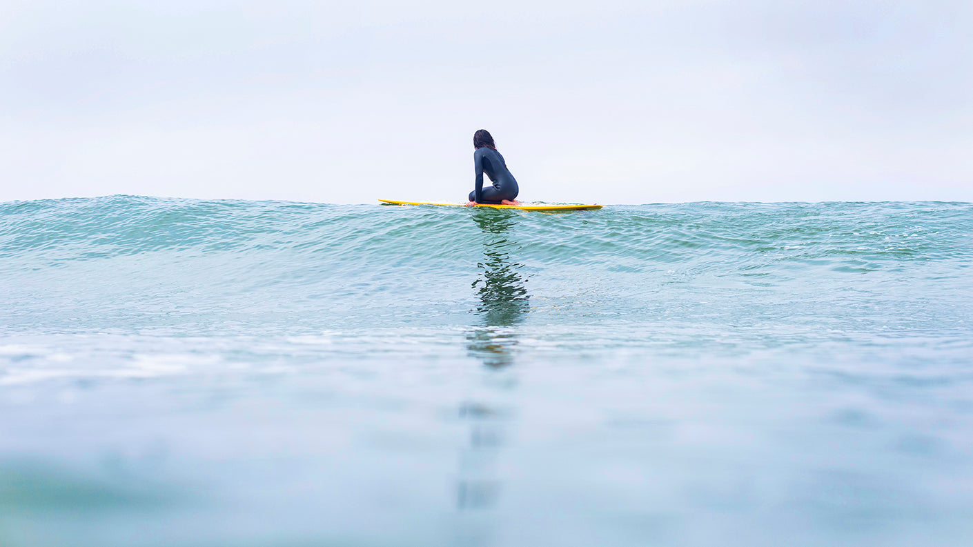 Woman on surfboard looking out at ocean.